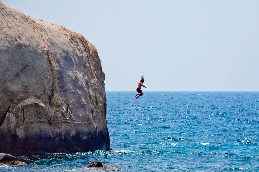 Man jumping off cliff into the sea