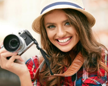 A beautiful tourist, smiling while holding a camera.