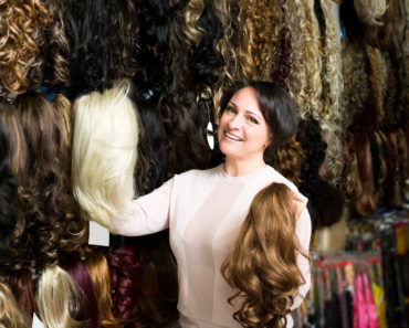A middle-aged woman assisting in a wig store.