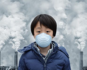A boy wears a face mask to shield himself from the harmful effects of toxic gases that are emitted by factories.