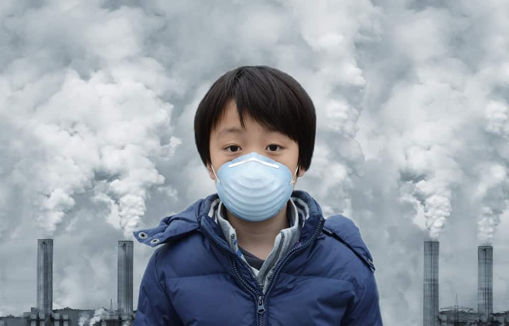 A boy wears a face mask to shield himself from the harmful effects of toxic gases that are emitted by factories.