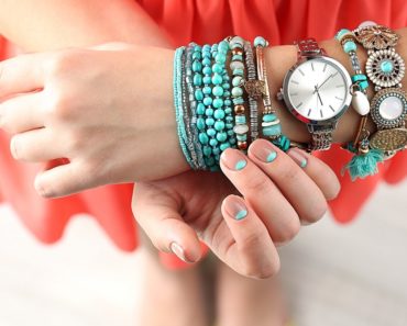 A lady is wearing her collection of beaded and charm bracelets.