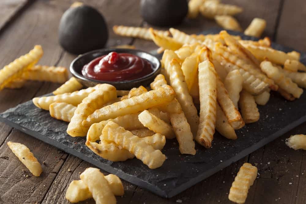 Crinkle fries with ketchup on the side.