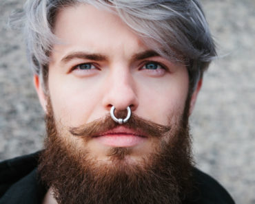A close up shot of a man with a nose piercing.