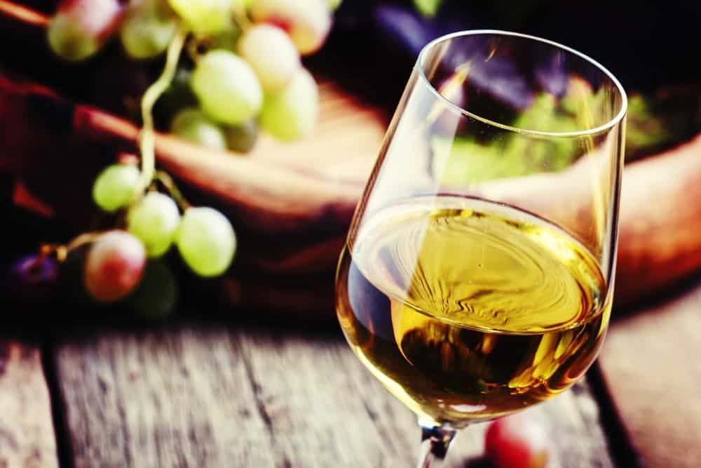 A picture of white wine in sparkling wine glass.