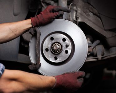 A mechanic is repairing a car brake.