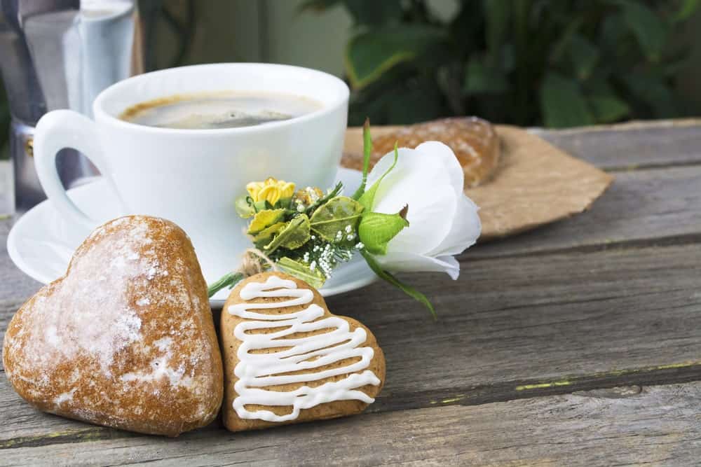 Heart-shaped cookies with a glass of milk on wooden table.