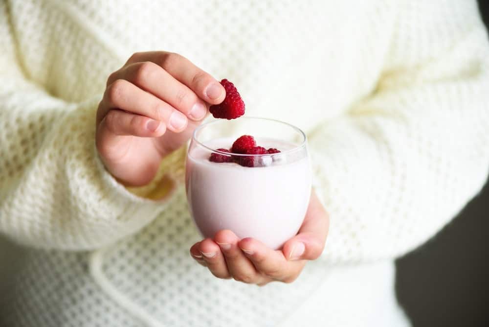 Person showing a glass of frozen kefir topped with strawberries.