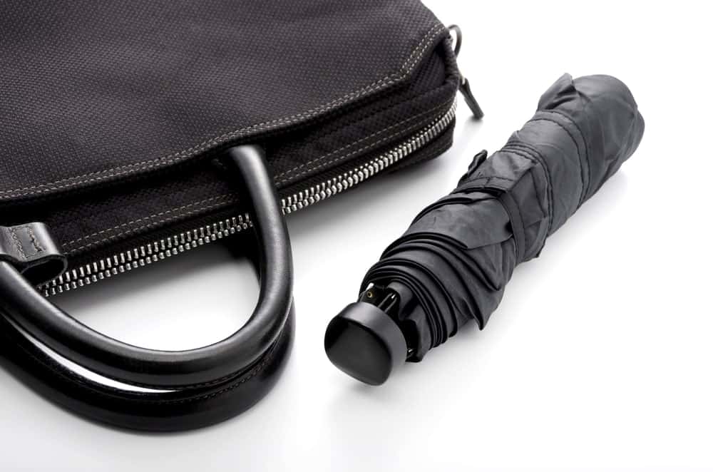 Compact umbrella beside a handbag.