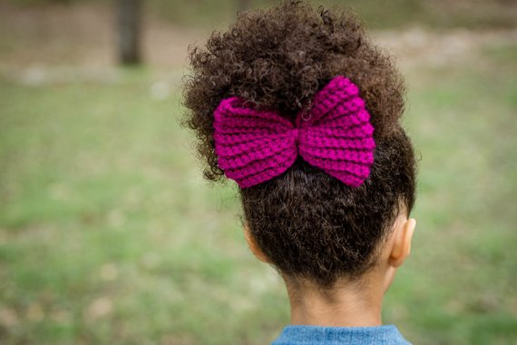 Back view of a young girl wearing a large yarn bow.