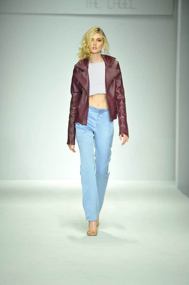 Model walking the rampway sporting a cropped jacket, top, and jeans.