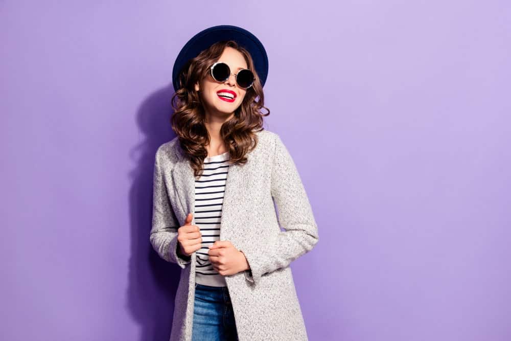 A girl posing in a fashionable outfit with a purple backdrop.