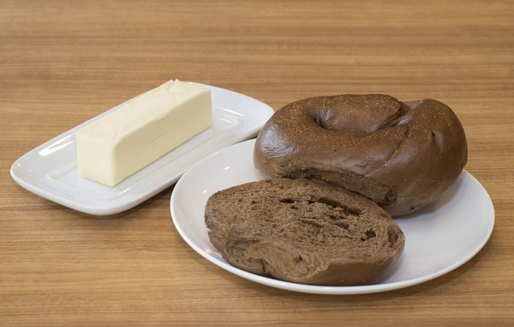 Two Pumpernickel Bagels on a White Plate