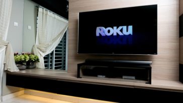 A wall-mounted smart TV showing the logo for Roku.