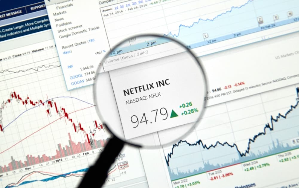 This is a close look at the stock market ticker of Netflix Inc. surrounded by graphs and tables.