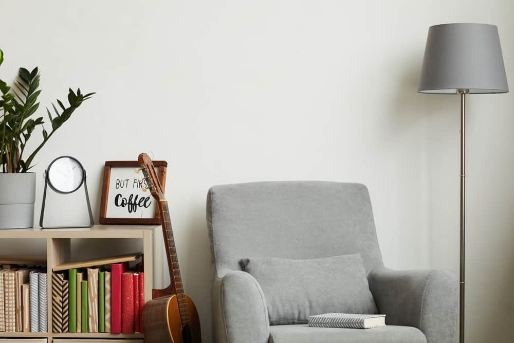 This is a close look at a gray cushioned Lawson chair paired with a gray standing lamp.