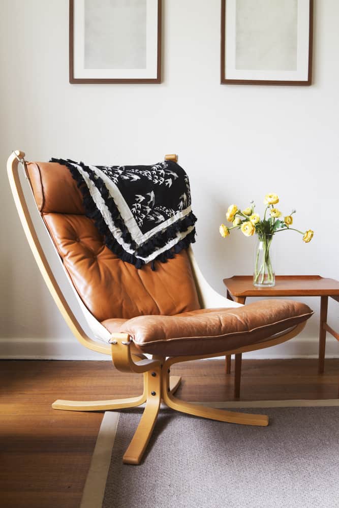 This is a close look at a reading nook with a vintage tan slipper chair and a side table.