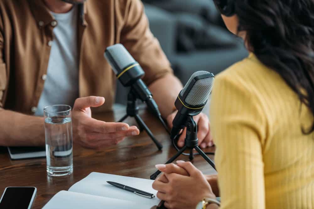 Two radio hosts recording podcast in broadcasting studio.