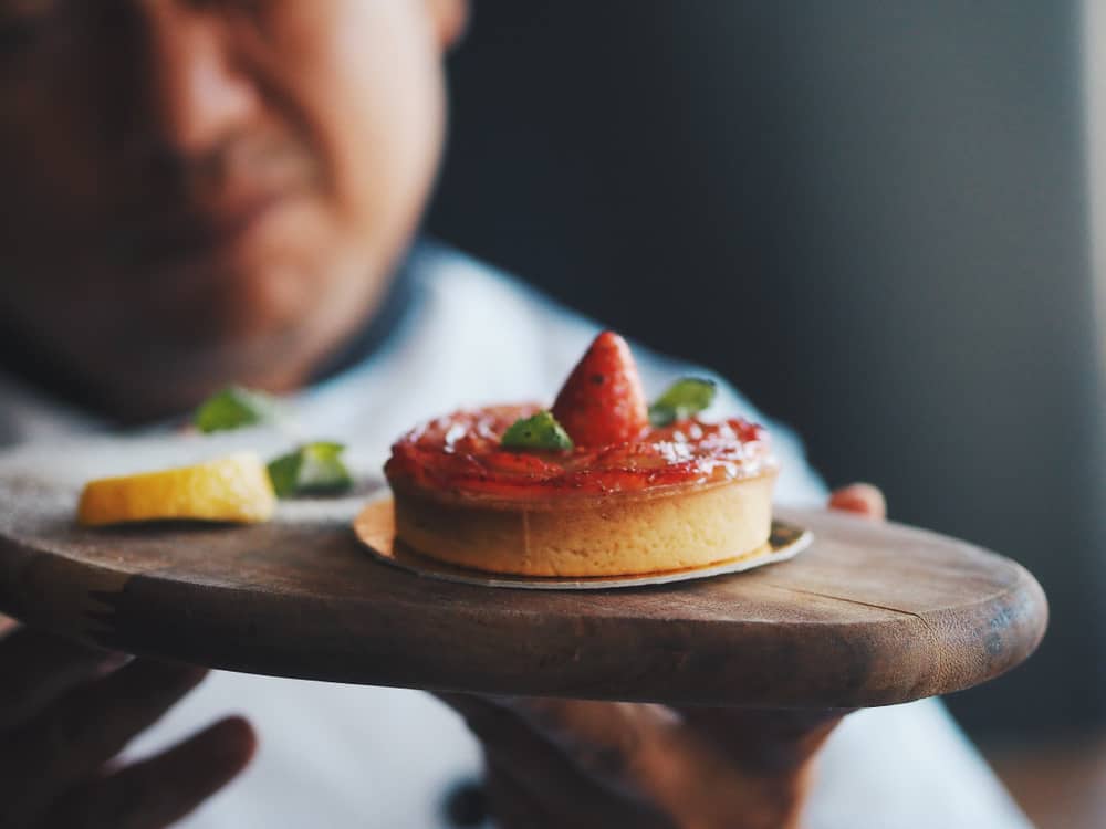 Master chef holding a strawberry tart.