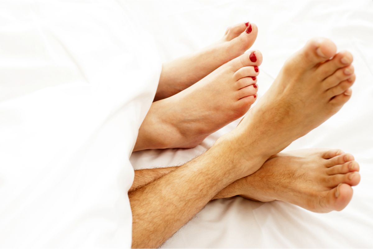 Closeup barefoot of a couple undersheets.