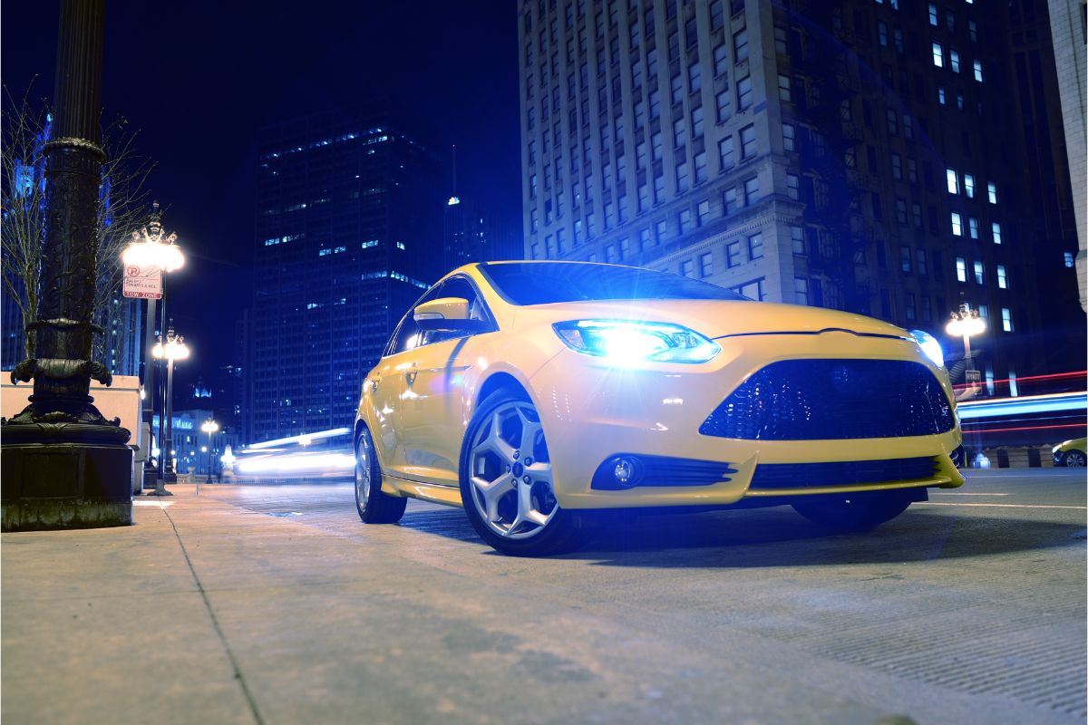 A yellow car on the street at night.