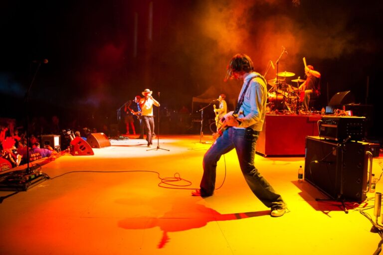 A band performing on stage with a yellow lights.