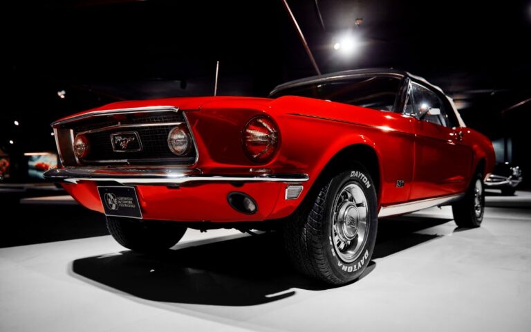 A red ford mustang convertible in a classic car exhibit.