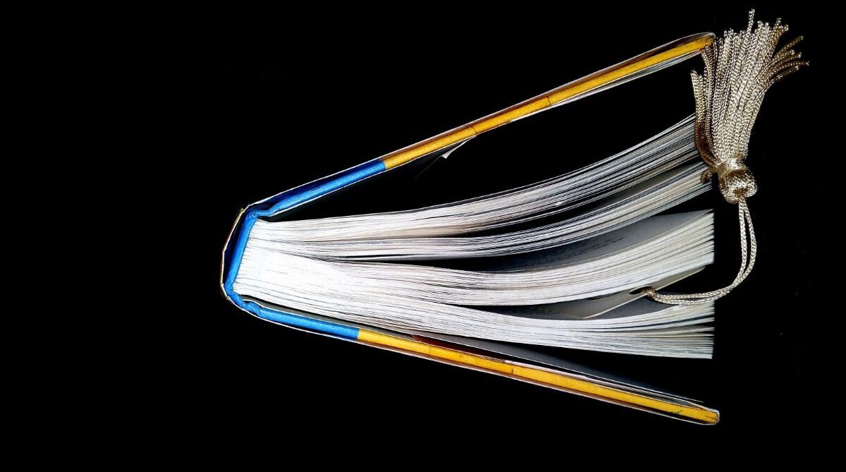 Book with a hardcover dust jacket in a black background.