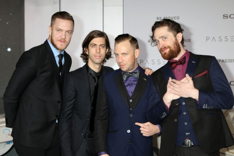 A group photo of imagine dragons band wearing formal suits.