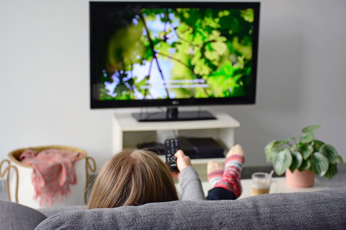 A girl watching nature documentaries while relaxing in her room.