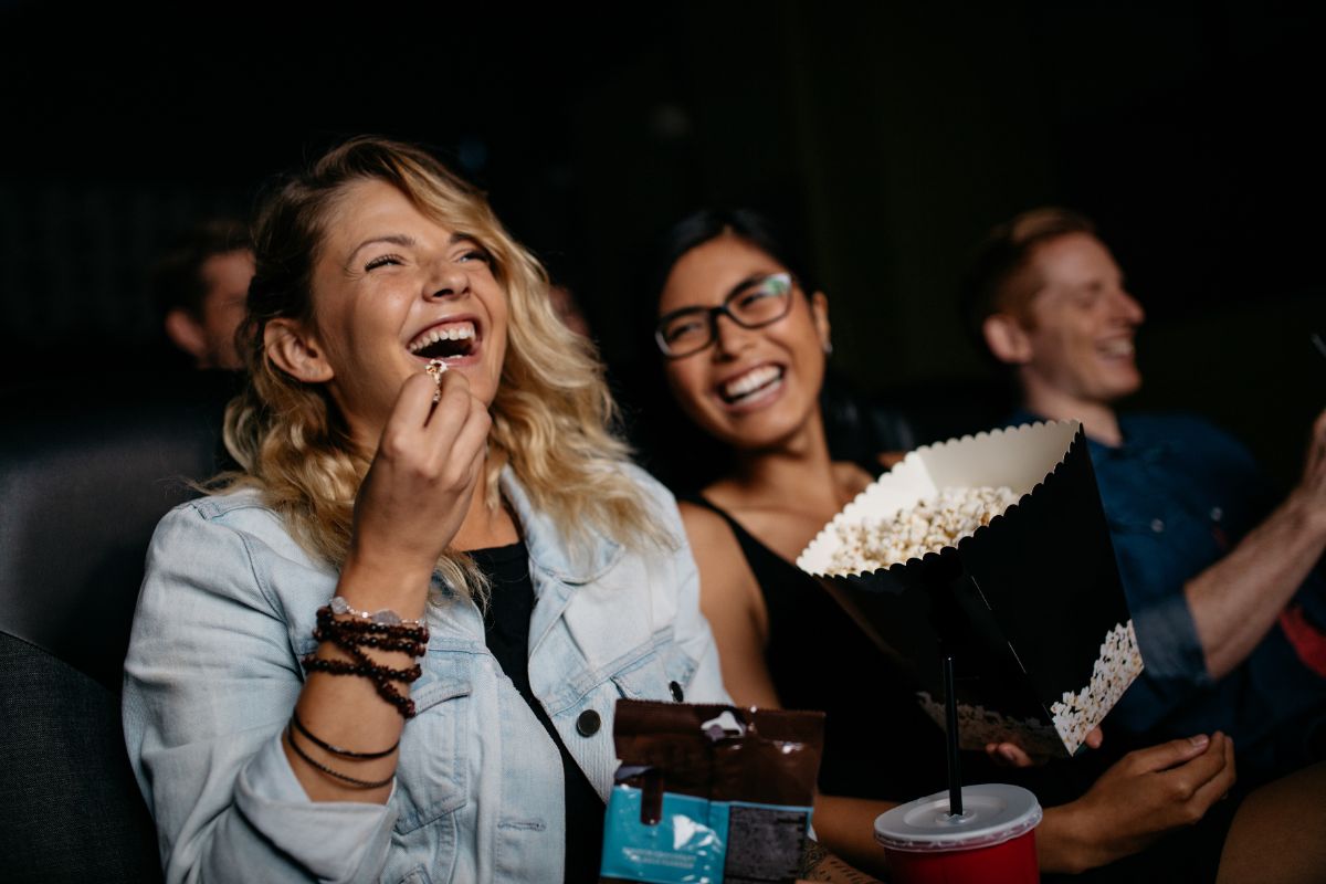 People laughing while watching a comedy movie in a theatre.